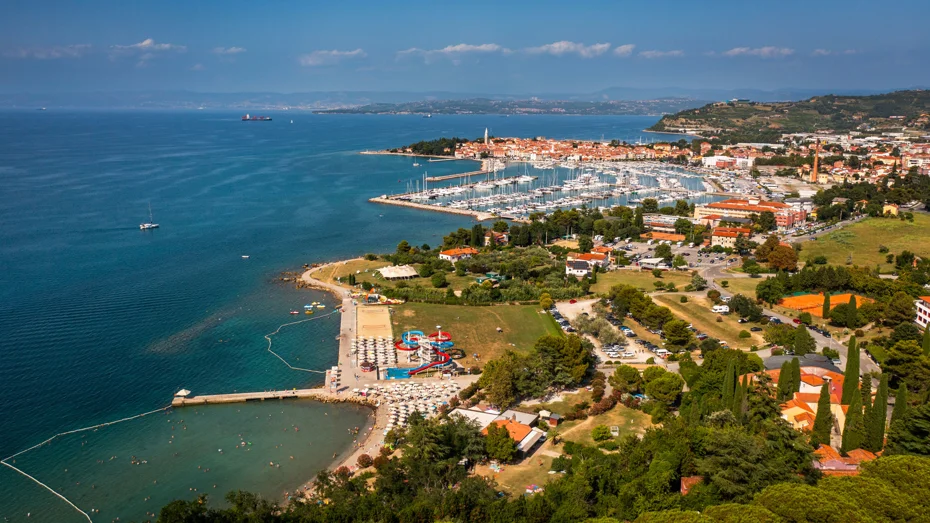 Panoramski pogled na slovensko obalo, ki vključuje pristanišče, hotelski kompleks, staro mestno jedro in zelene površine