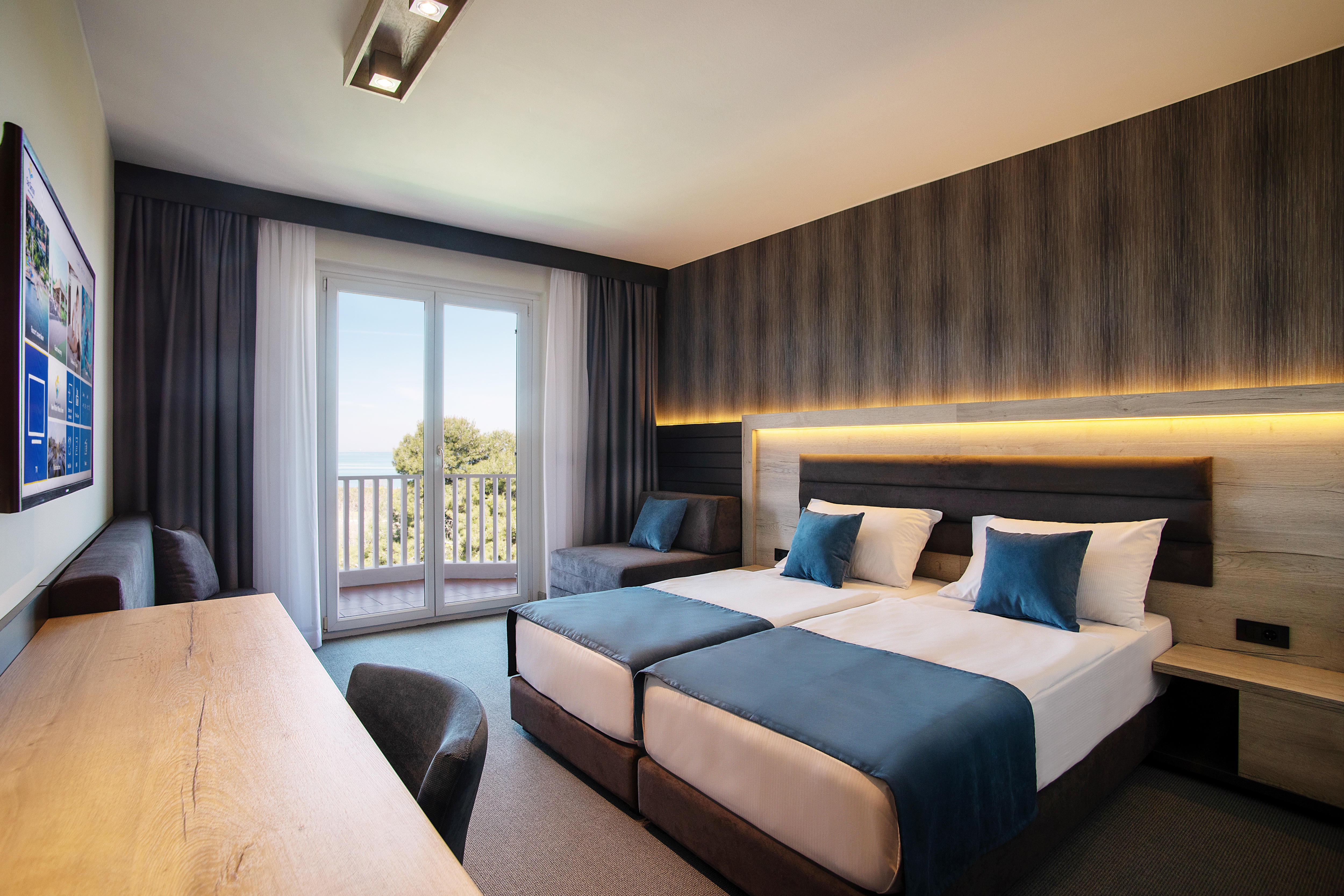 Prostorna hotelska soba lesenega videza in modrih odtenkov