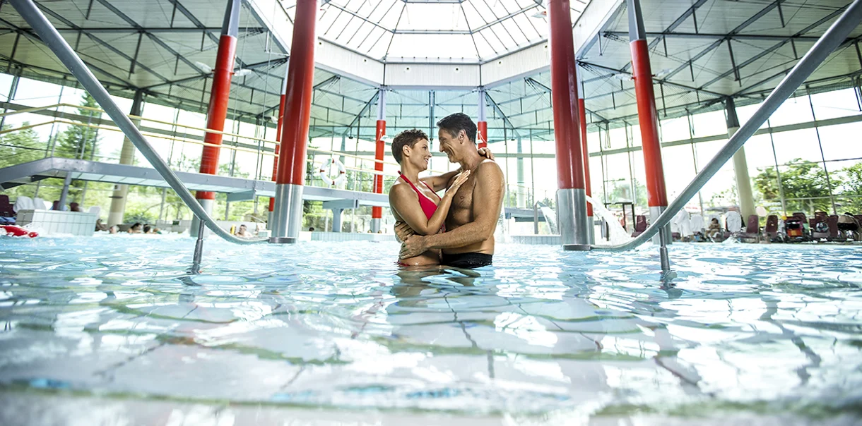 Par v kopalkah se na sredini notranjega bazena objema in nasmiha