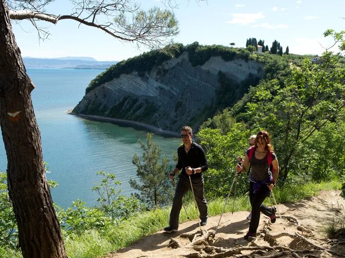Moški in ženska se v pohodniški opremi sprehajata ob klifu v Mesečevem zalivu