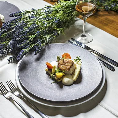 Dekorirana miza s prtom, dvema kozarcema alkoholne pijače in dvema krožnikoma privlačne jedi