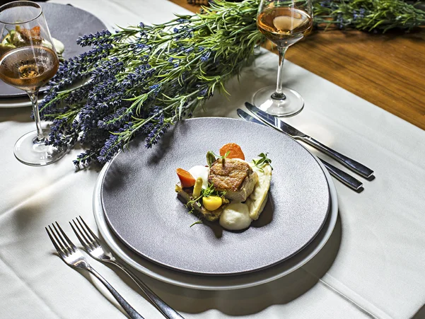 Dekorirana miza s prtom, dvema kozarcema alkoholne pijače in dvema krožnikoma privlačne jedi